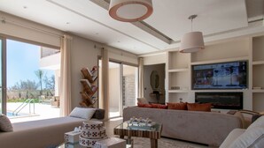 Un salón amplio con un televisor grande, asientos cómodos y vistas al exterior.