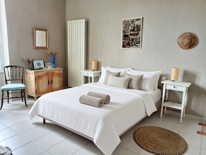 A neatly arranged bedroom with a bed, bedside tables, a chair, and a dresser.