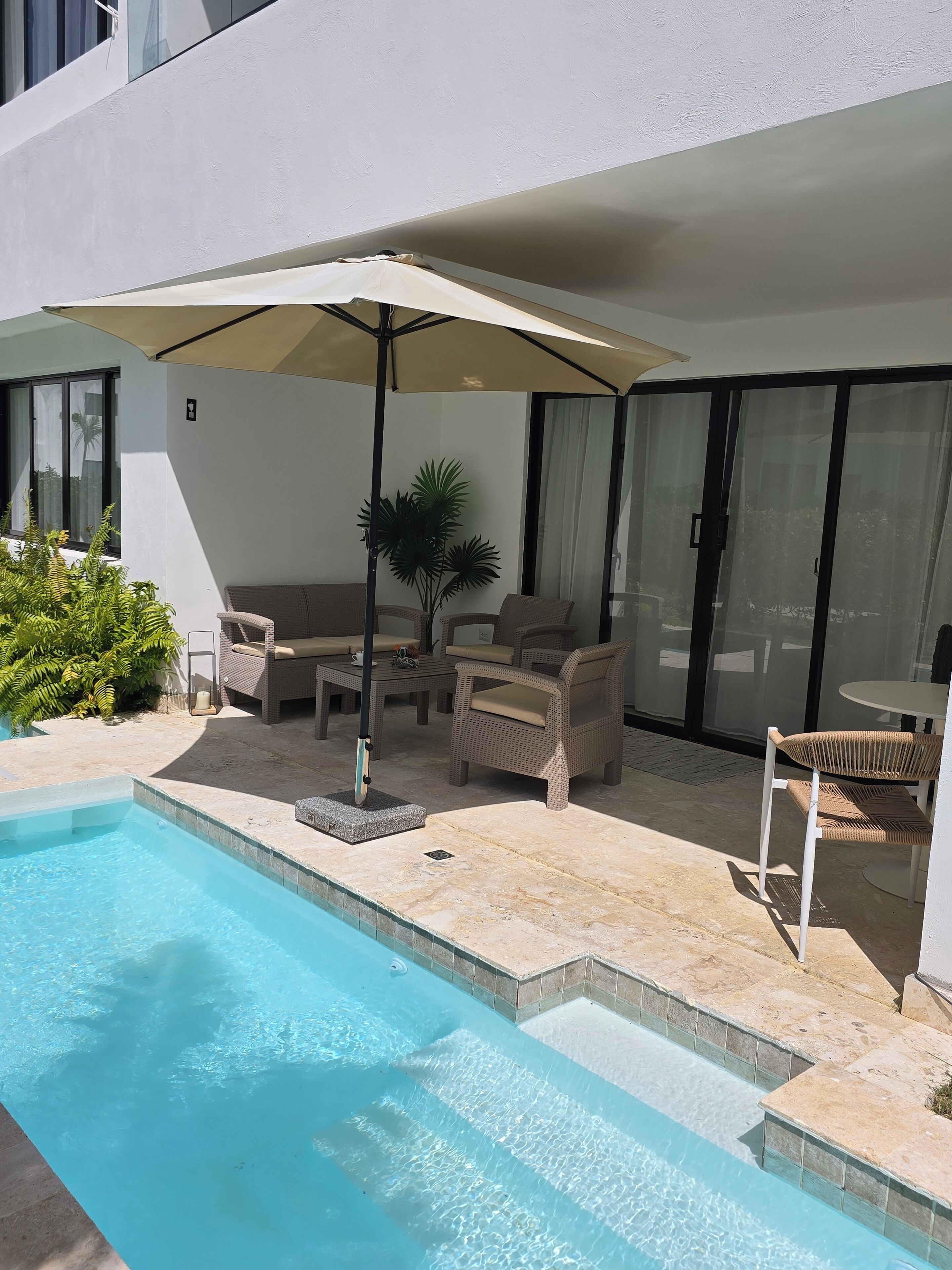 A pool area with a lounge chair, a table, and an umbrella.