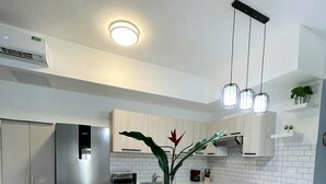A modern kitchen with a stainless steel refrigerator, wooden cabinets, a white countertop, and two bar stools. - Family-Friendly White Sands 2BR - Private Pool, Fast Wi-Fi, Near Beach (Punta Cana)