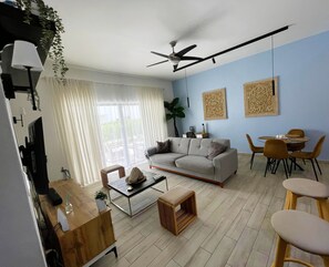 Ein modernes Wohnzimmer mit Sofa, Couchtisch und Essbereich.