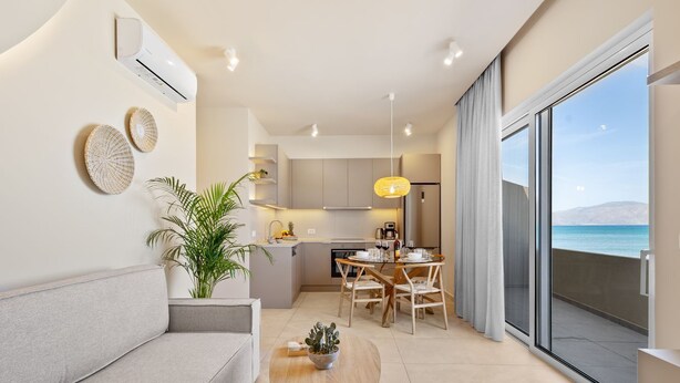 Un appartement moderne comprenant un coin repas, une cuisine et un balcon avec vue sur la mer.