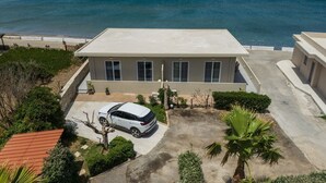 Une maison moderne à deux étages, dotée d’un toit plat, d’une allée et d’un VUS garé.