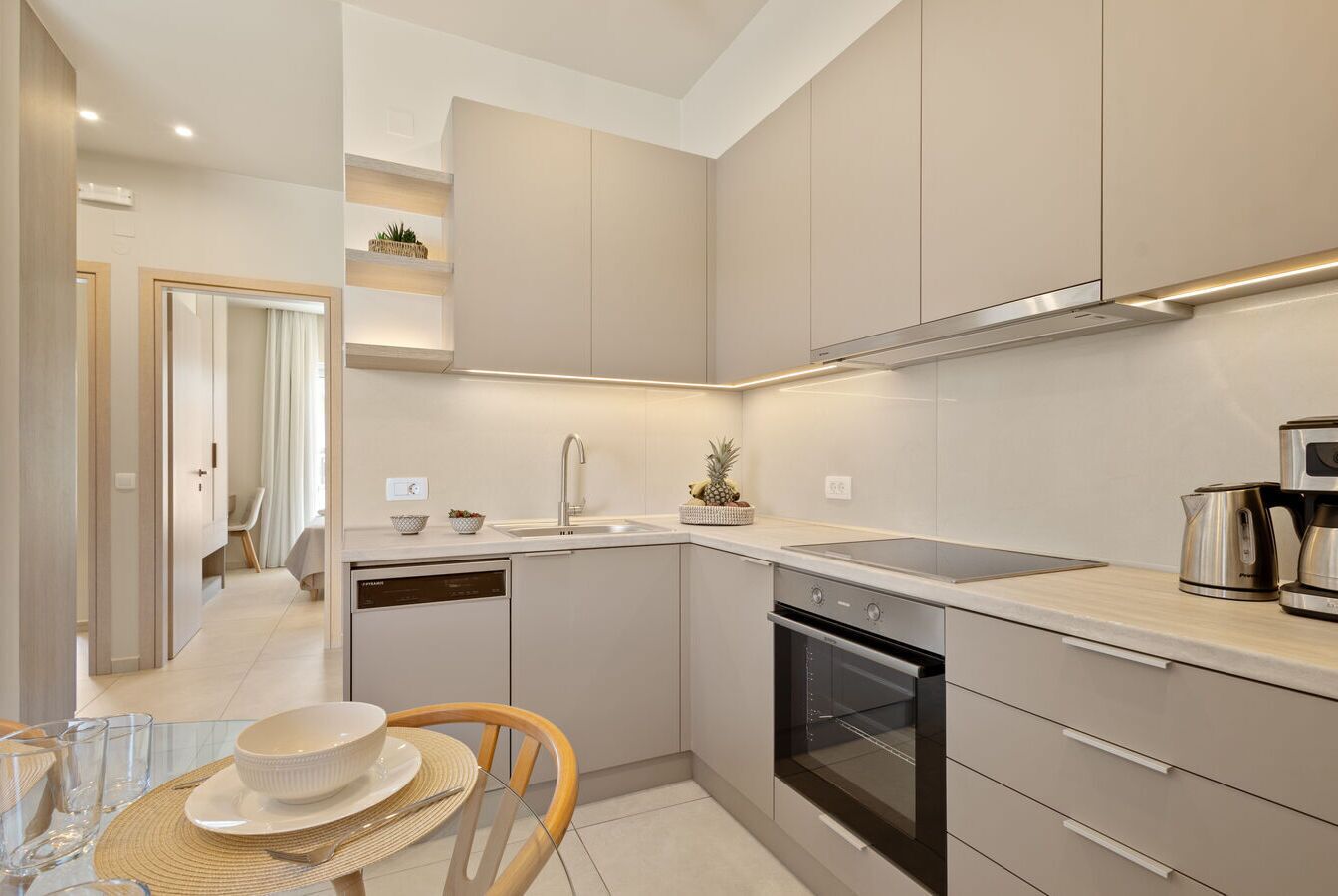A modern kitchen with a dishwasher, oven, and a coffee maker on the counter.