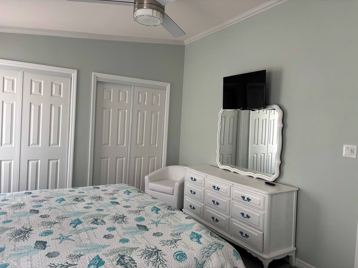 A bedroom with a bed, dresser, and a ceiling fan.