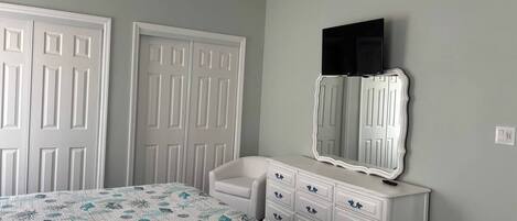 A bedroom with a bed, dresser, and a ceiling fan.