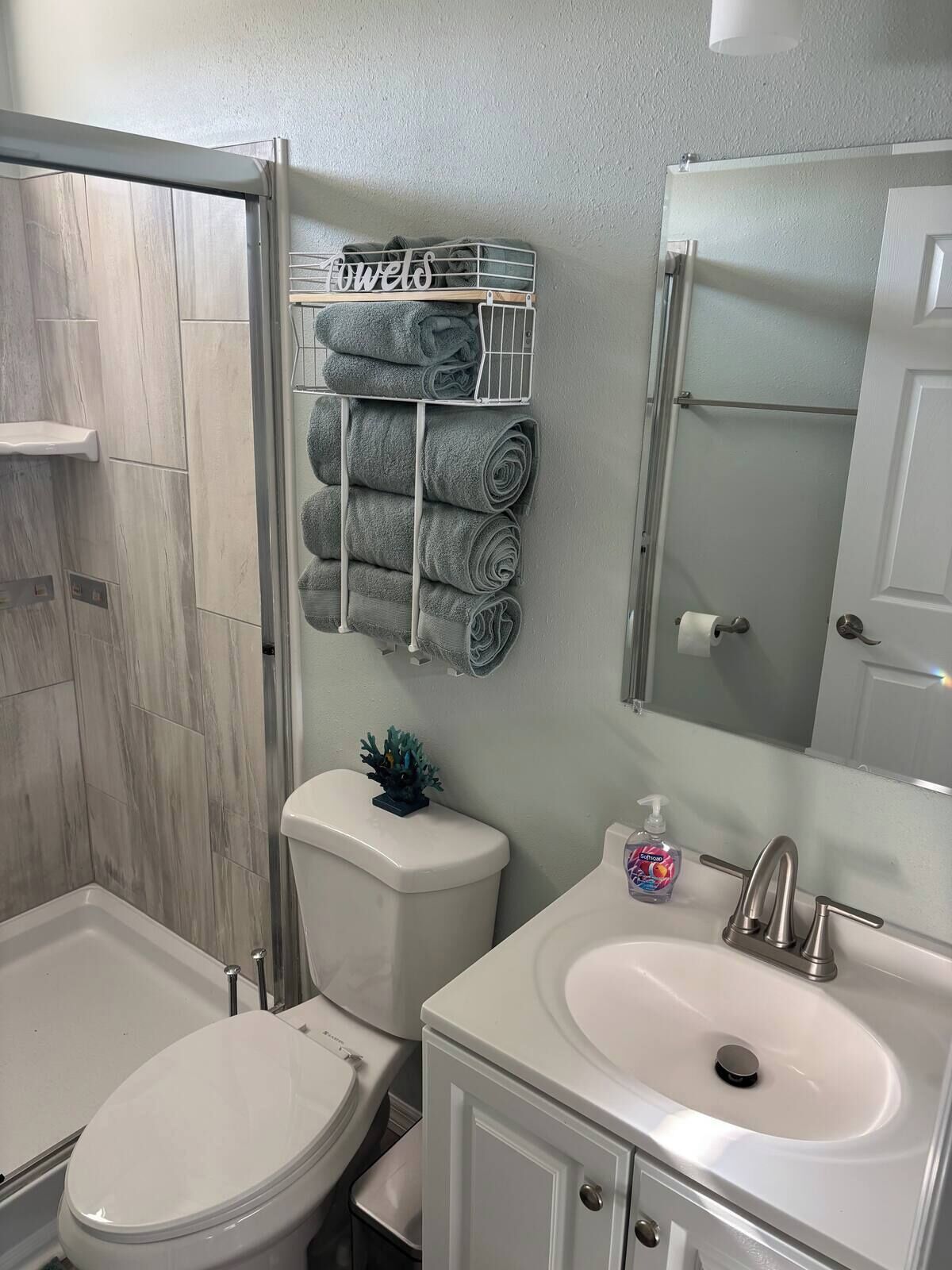 A bathroom with a toilet, sink, and a towel rack with towels.