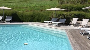 Una piscina cristalina con sillas de descanso y sombrillas.