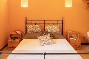 Ein Bett mit Metallgestell, zwei Nachttische aus Holz und ein Kissen mit Muster.