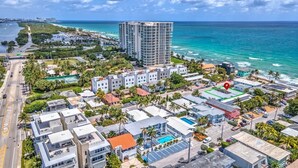 An aerial view of a coastal urban area with modern buildings, a large hotel, and a view of the ocean. - Cozy 1BR Seaside, Steps to Hollywood Beach & More (Hollywood)