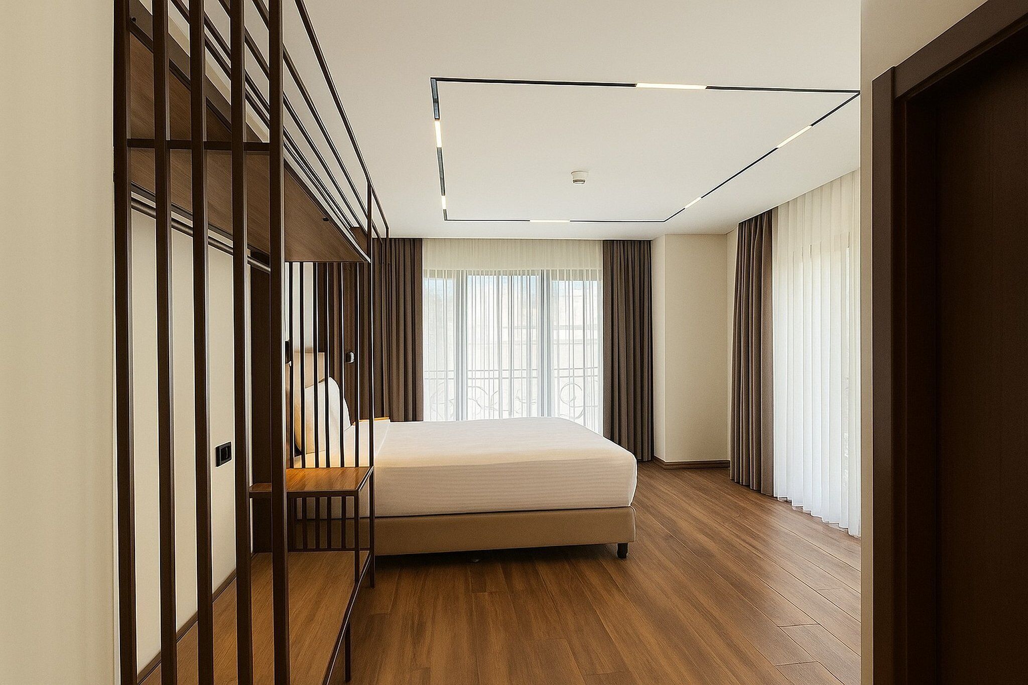 A modern bedroom with a bed, wooden flooring, and a large window with curtains.