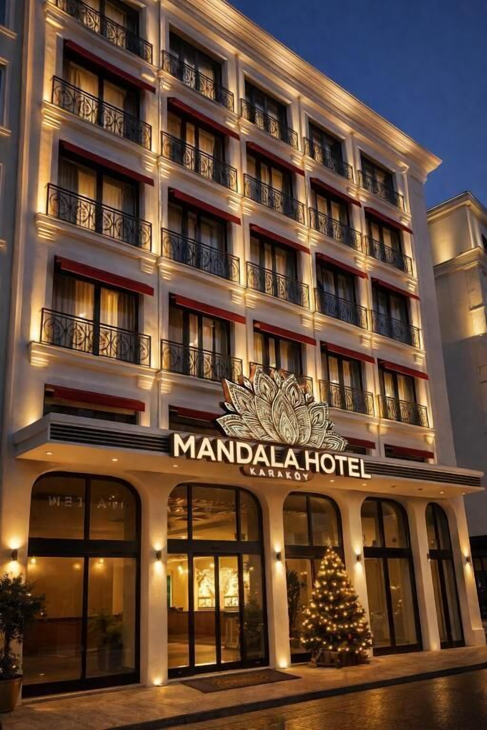 A multi-story hotel with balconies, a Christmas tree, and a sign reading 'MANDALA HOTEL KARAKOV'.