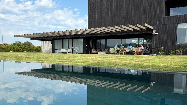 A modern building with a pool, outdoor seating, and a clear sky.