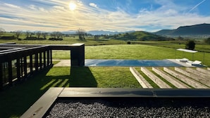 A pool area with a view of a grassy landscape and hills in the background.