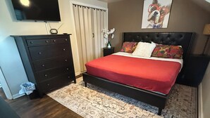 Ein Schlafzimmer mit Bett, Kommode, Fernseher und Deckenventilator.