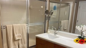 Une salle de bain avec une douche à parois de verre, un meuble-lavabo avec un miroir et un banc.