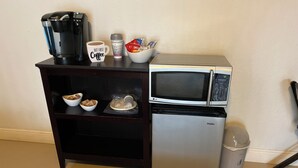 Une petite cuisine équipée d’une machine à café, d’un four à micro-ondes et d’étagères de rangement.