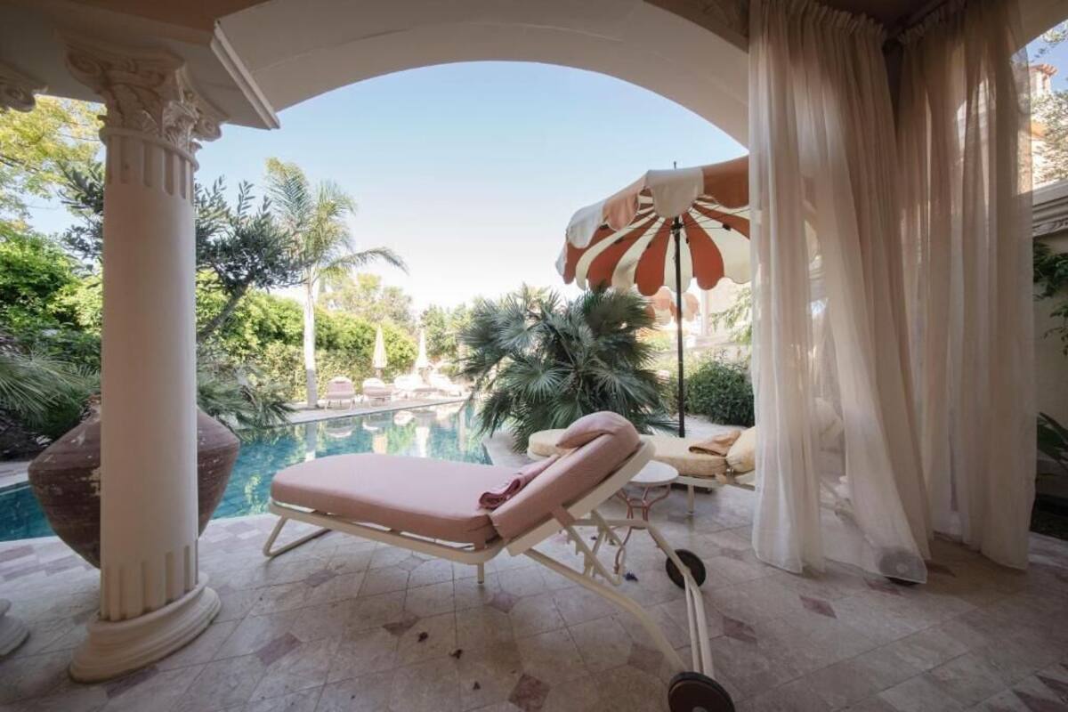A sun lounger by a pool with a view of palm trees and a clear sky.