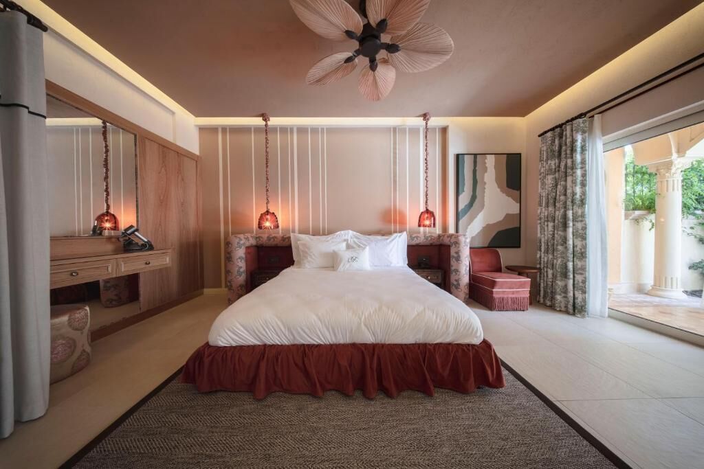 A bedroom with a large bed, a desk, and a ceiling fan.