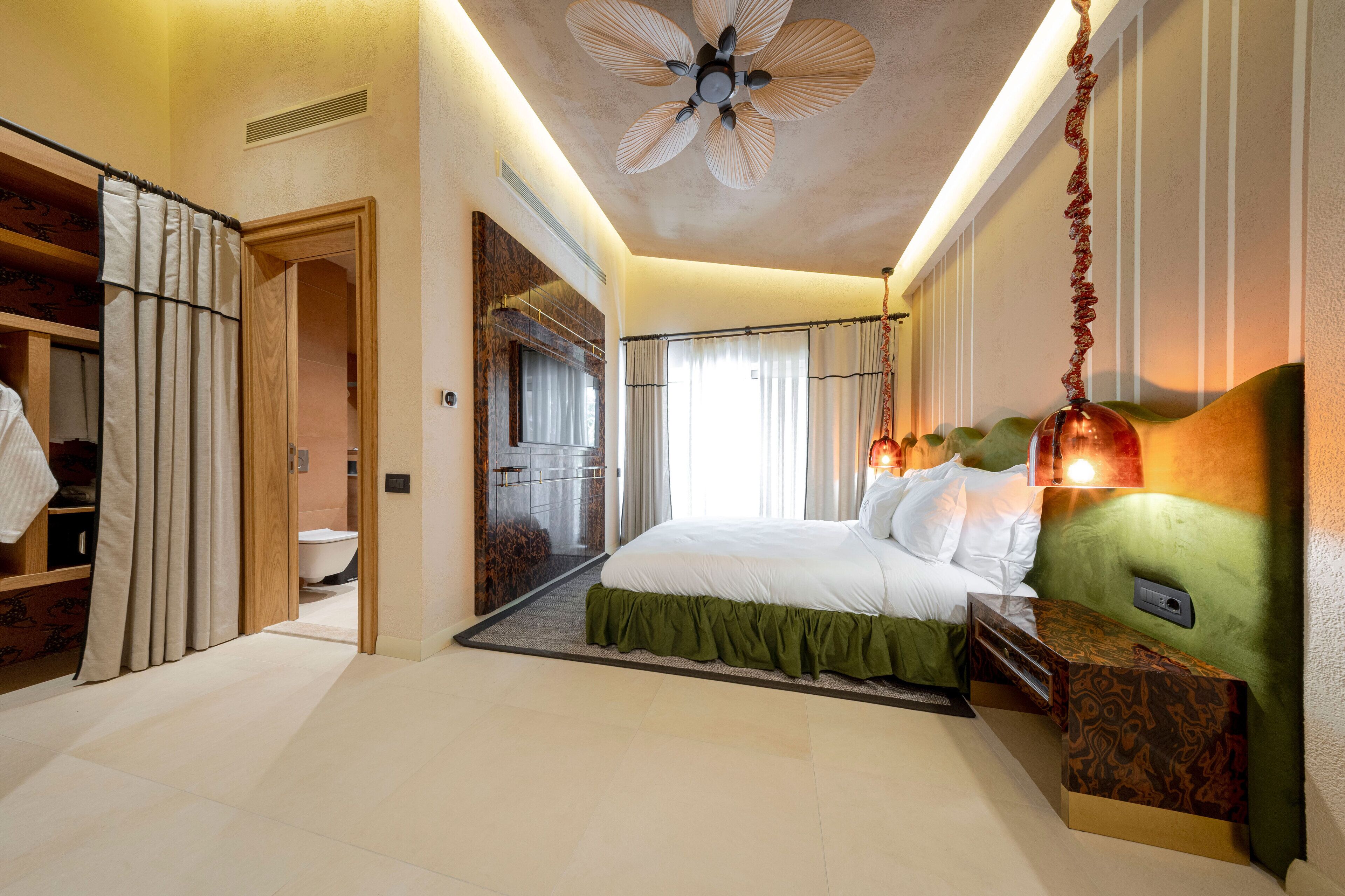 Une chambre d’hôtel équipée d’un lit, d’une coiffeuse, d’une douche et d’un ventilateur de plafond.