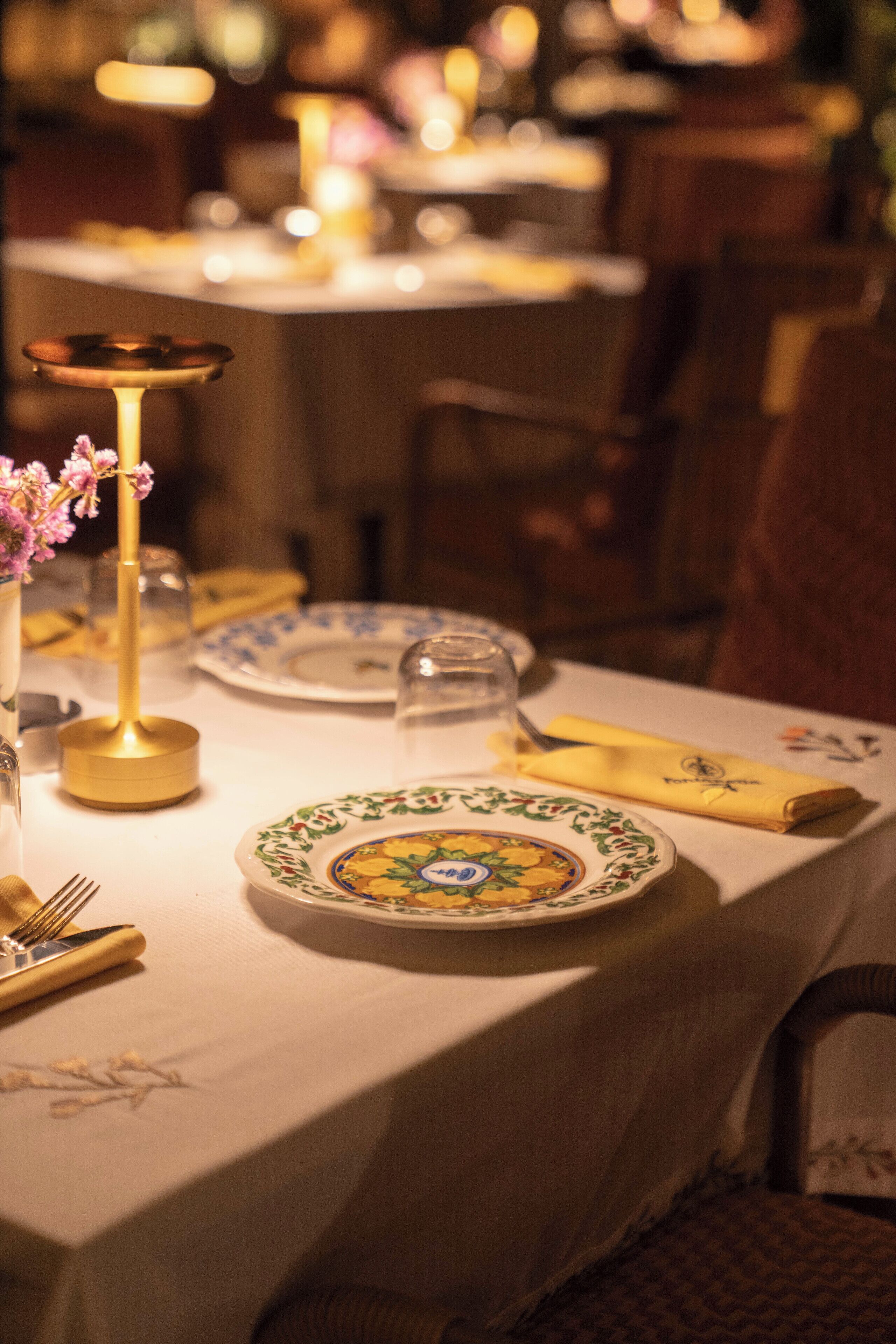 A dining table set with plates, cutlery, and a candle holder.
