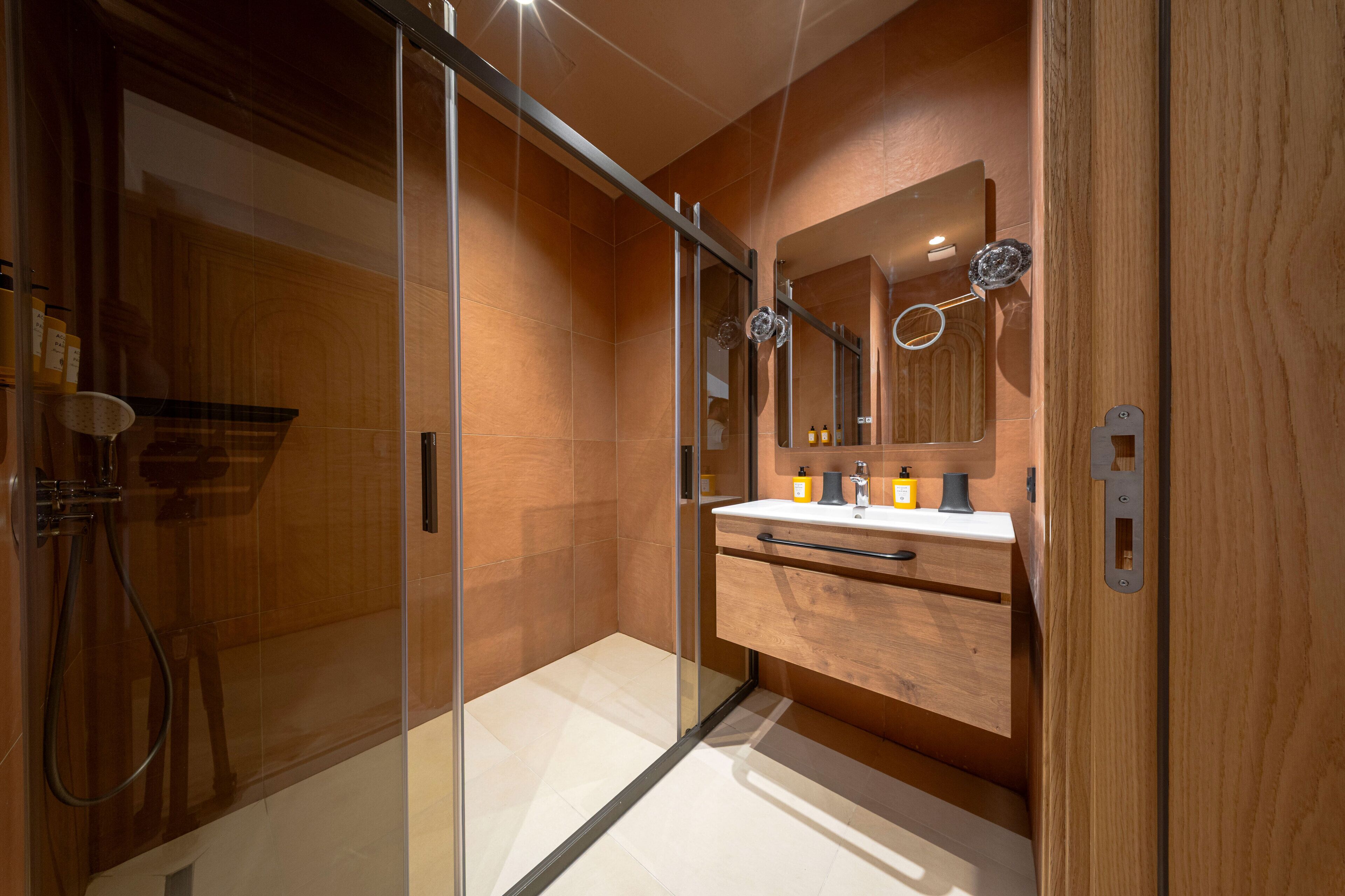 Une salle de bain moderne avec une douche à parois de verre, un meuble-lavabo en bois et un grand miroir.