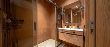 Une salle de bain moderne avec une douche à parois de verre, un meuble-lavabo en bois et un grand miroir.