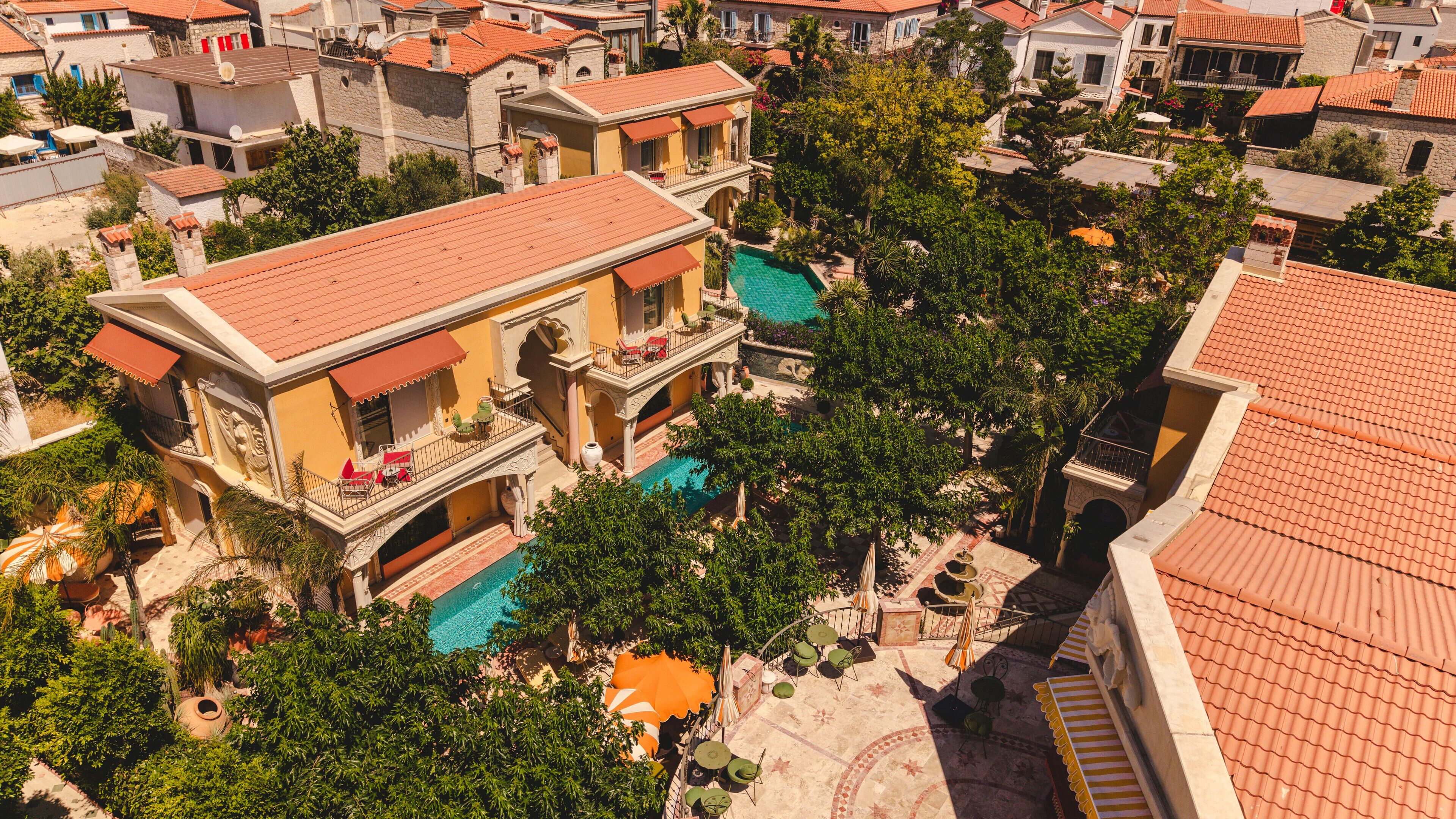 Uma villa em estilo mediterrâneo com piscina, várias varandas e vegetação exuberante.