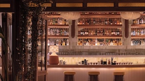 A bar area with a wooden ceiling, multiple shelves of bottles, and a bar counter. - Hotel Casa Fontana (Cesme)