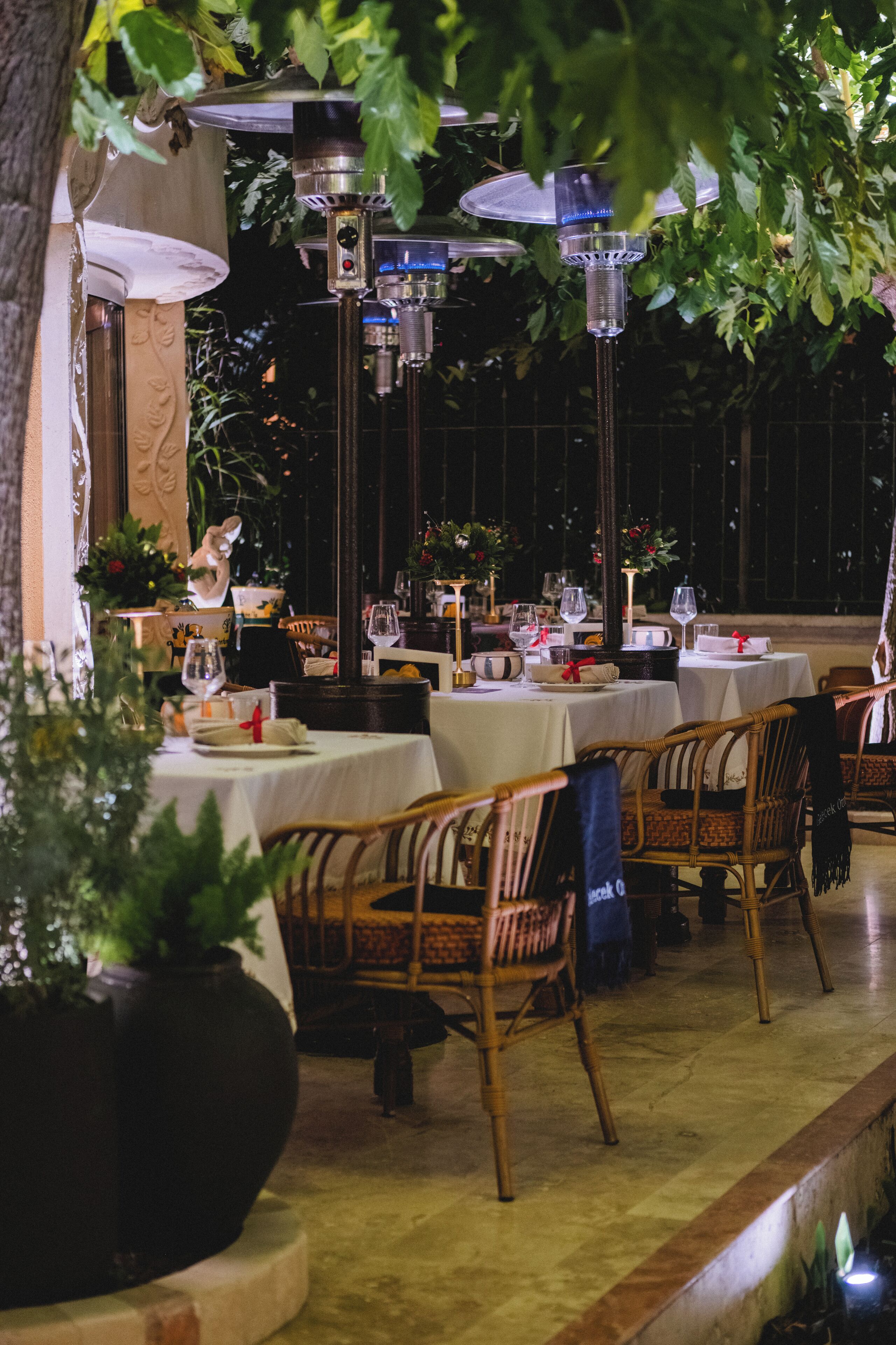 An outdoor dining area with tables, chairs, and hanging lamps.