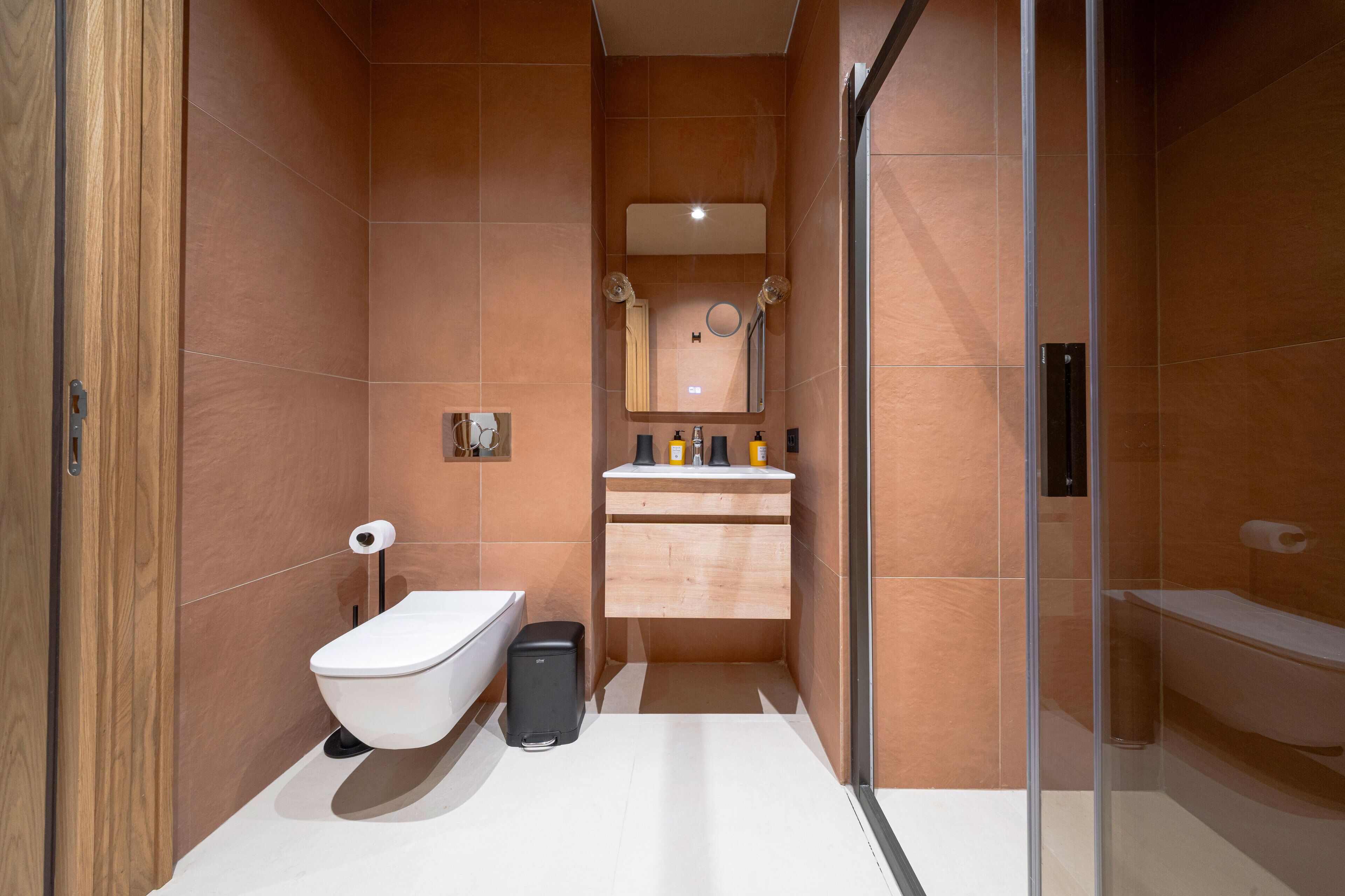 A modern bathroom with a toilet, bidet, and a glass shower enclosure.