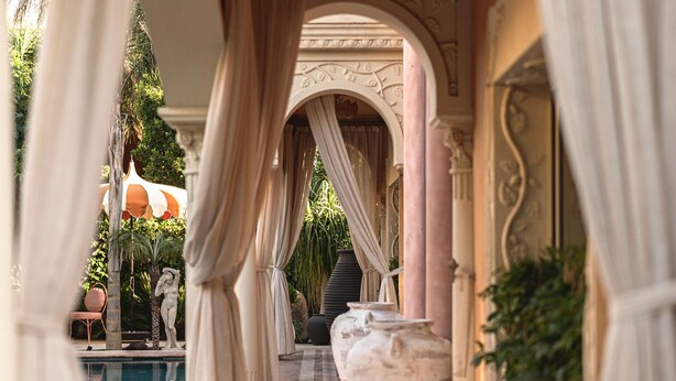 A luxurious pool area with a marble pathway, columns, and a statue. - Hotel Casa Fontana (Cesme)