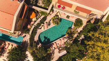 Vista aérea de un hotel con una amplia piscina, zonas de estar al aire libre y abundante vegetación.
