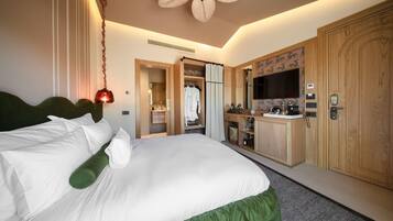 A hotel room with a large bed, a wardrobe, a vanity with a mirror, and a ceiling fan.