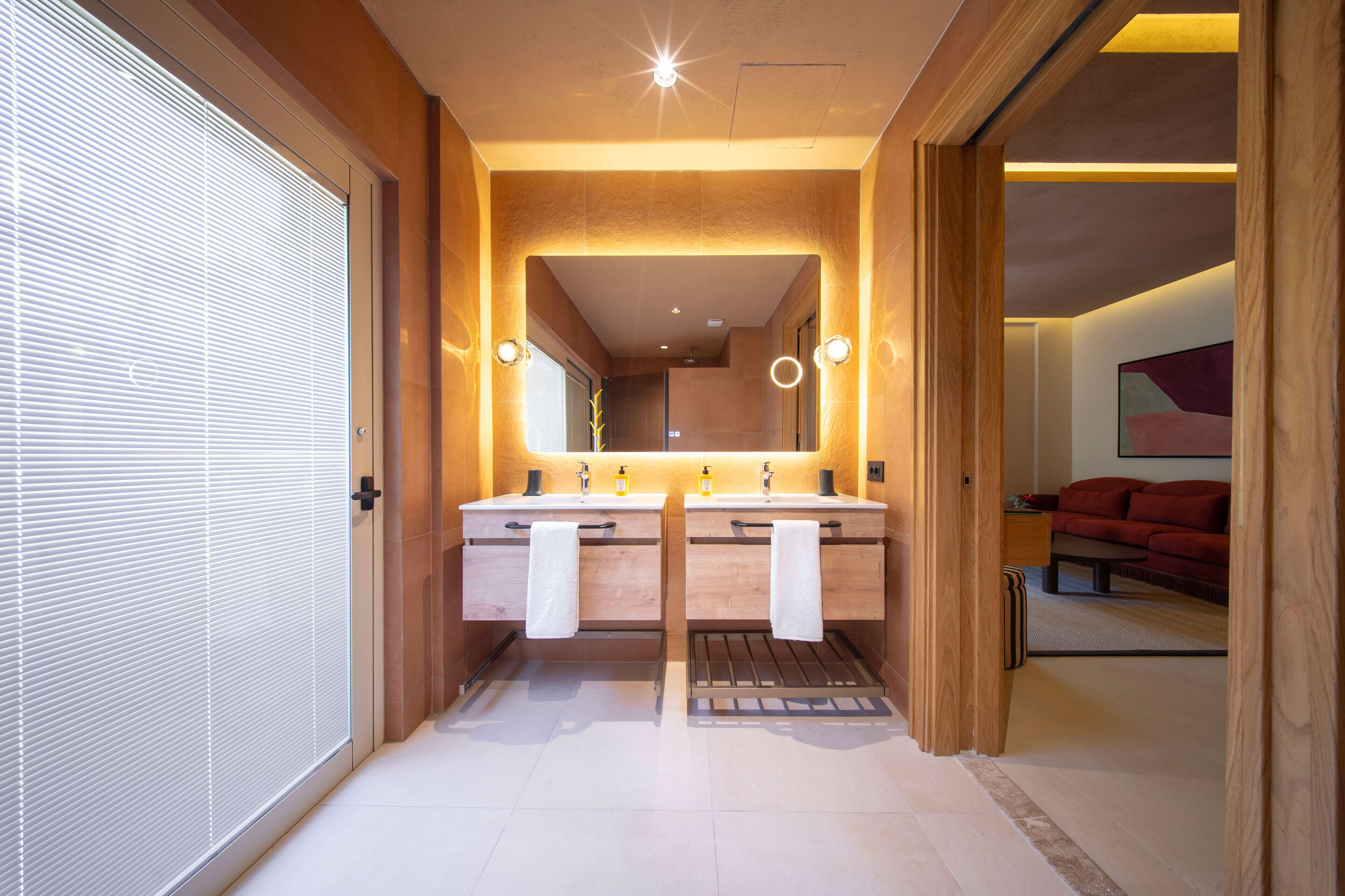 A modern bathroom with two sinks, a large mirror, and a wooden vanity.