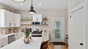 A modern kitchen with white cabinets, a central island, and a hanging pendant light.