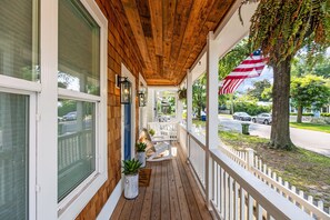 Eine Holzveranda mit weißer Geländer, Blumentöpfen und einer amerikanischen Flagge.