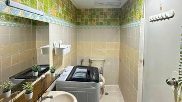 A compact bathroom with a sink, two toilets, and a shower area.