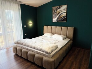 Een slaapkamer met een bed, een wandlamp en een schilderij.