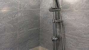 Eine Dusche mit Handbrause und Kopfbrause, beide mit Chromarmaturen, an einer Wand mit grauen Marmorfliesen angebracht.