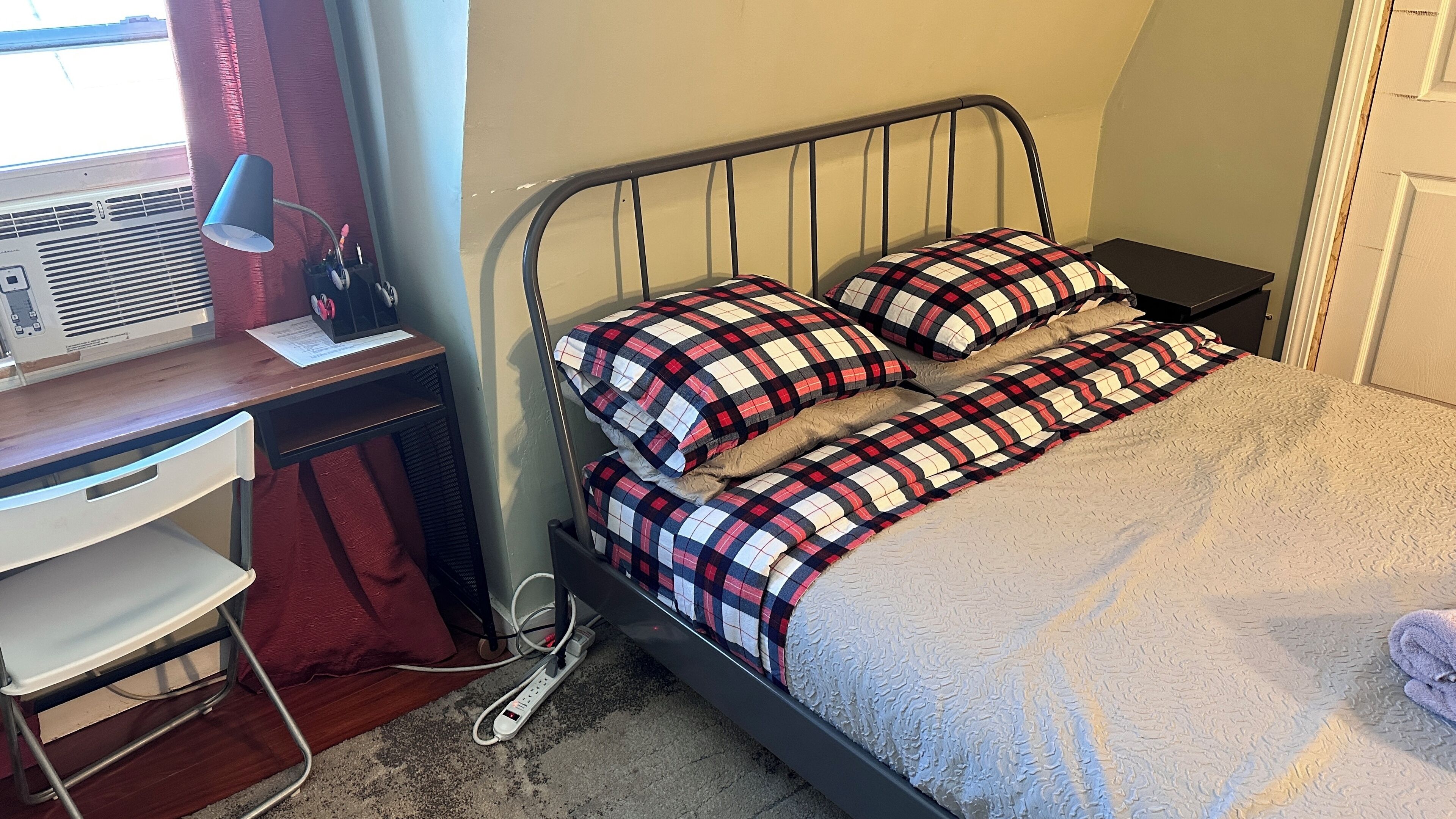 Un dormitorio con cama, escritorio y silla.