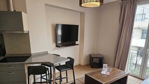 A modern kitchen with a built-in stove, a dining area with a table and chairs, a flat-screen TV mounted on the wall, and a large window with a view of the outside. - Charming 2-bedroom apartment in beautiful Lastarria Santiago with AC, WiFi (Santiago)