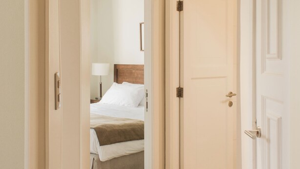 A hotel hallway leading to a bedroom with a bed, a nightstand, and a lamp. - Charming 2-bedroom apartment in beautiful Lastarria Santiago with AC, WiFi (Santiago)