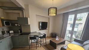 A modern kitchen with a microwave, toaster, and kettle, a dining area with a table and chairs, a flat-screen TV, and a sofa with a lamp. - Charming 2-bedroom apartment in beautiful Lastarria Santiago with AC, WiFi (Santiago)