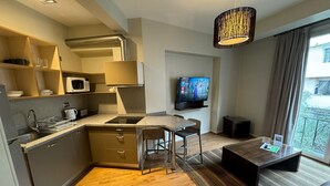 A compact kitchen with a microwave, sink, and a dining area with stools. A flat-screen TV is mounted on the wall, and there's a balcony with a view. - Charming 2-bedroom apartment in beautiful Lastarria Santiago with AC, WiFi (Santiago)