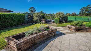 A landscaped garden with a stone patio, a wooden planter, and a well-maintained lawn.