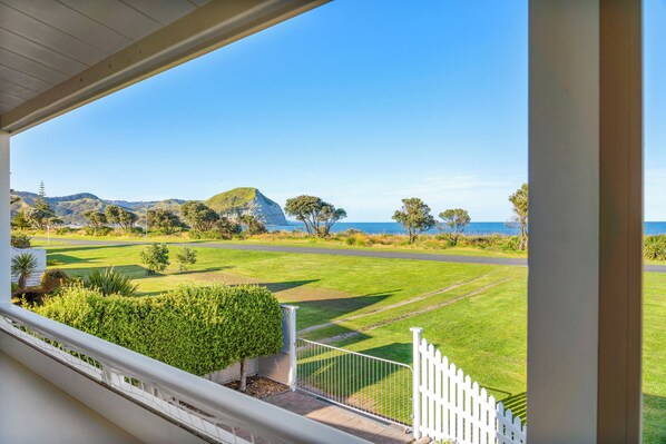 Uitzicht vanaf een balkon op een golfbaan, met een heldere lucht en heuvels in de verte.
