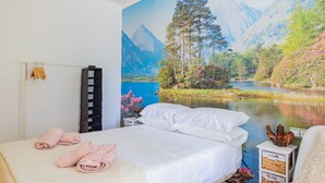A bedroom with a bed, a nightstand, and a wall mural of a mountain landscape.