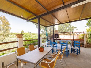 Une terrasse extérieure avec une table et des chaises, un four à pizza et une vue sur le paysage environnant.