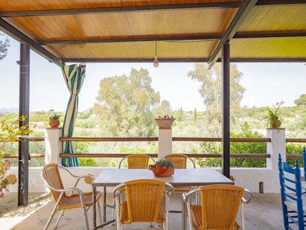 Une terrasse extérieure avec une table et des chaises, une pergola et une vue sur le paysage environnant.